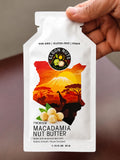 Hand holding an Elgon Nuts premium macadamia nut butter 1.15 oz single-serve packet.