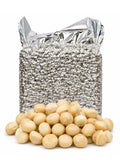 Whole raw macadamia nuts displayed in front of a large silver insulated bulk packaging bag.